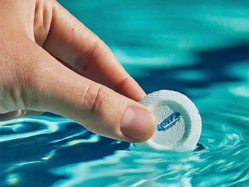 A person adding a Trichloroisocyanuric Acid tablet to a swimming pool